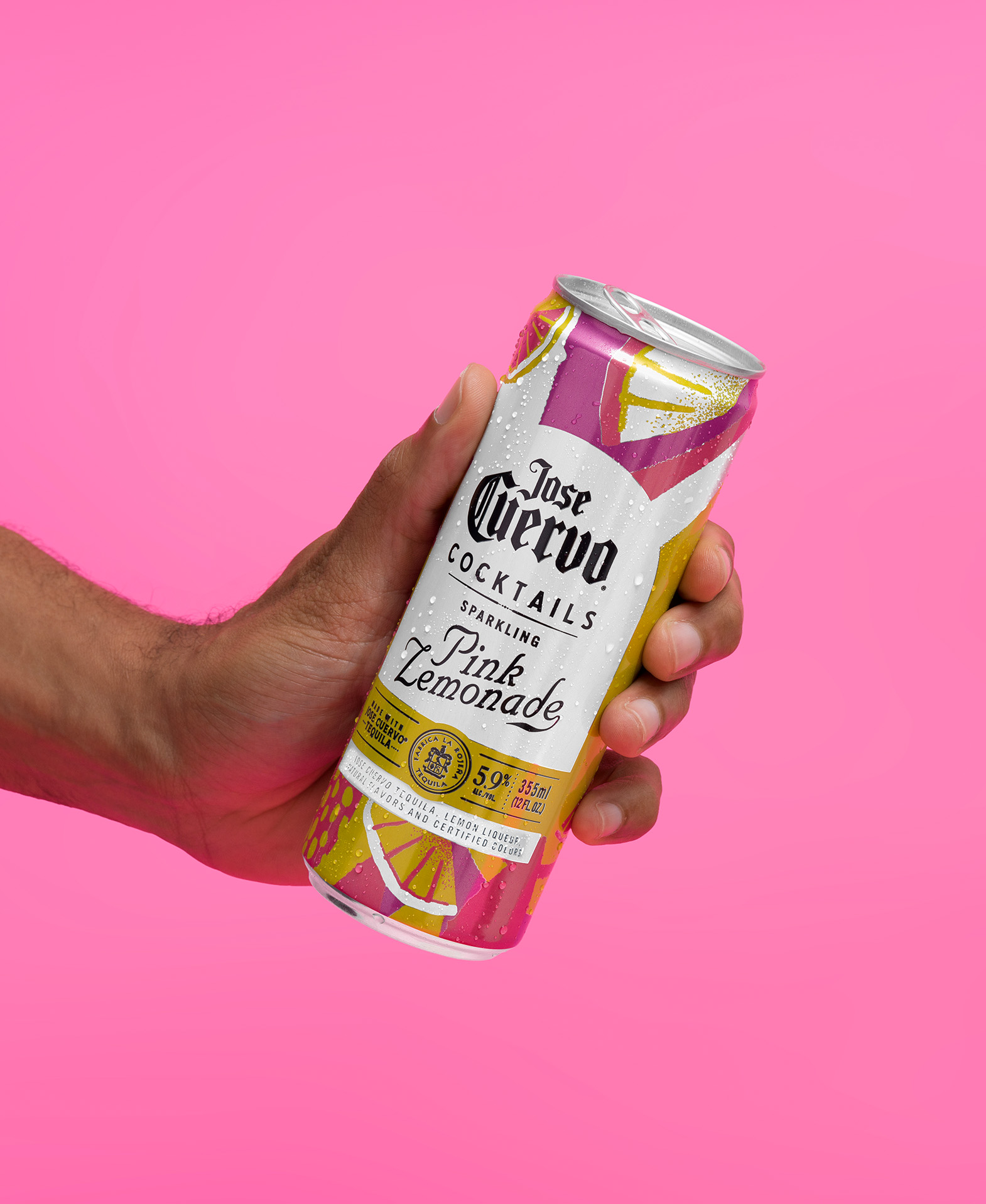 Hand holding a Jose Cuervo Sparkling Pink Lemonade cocktail can against a pink background