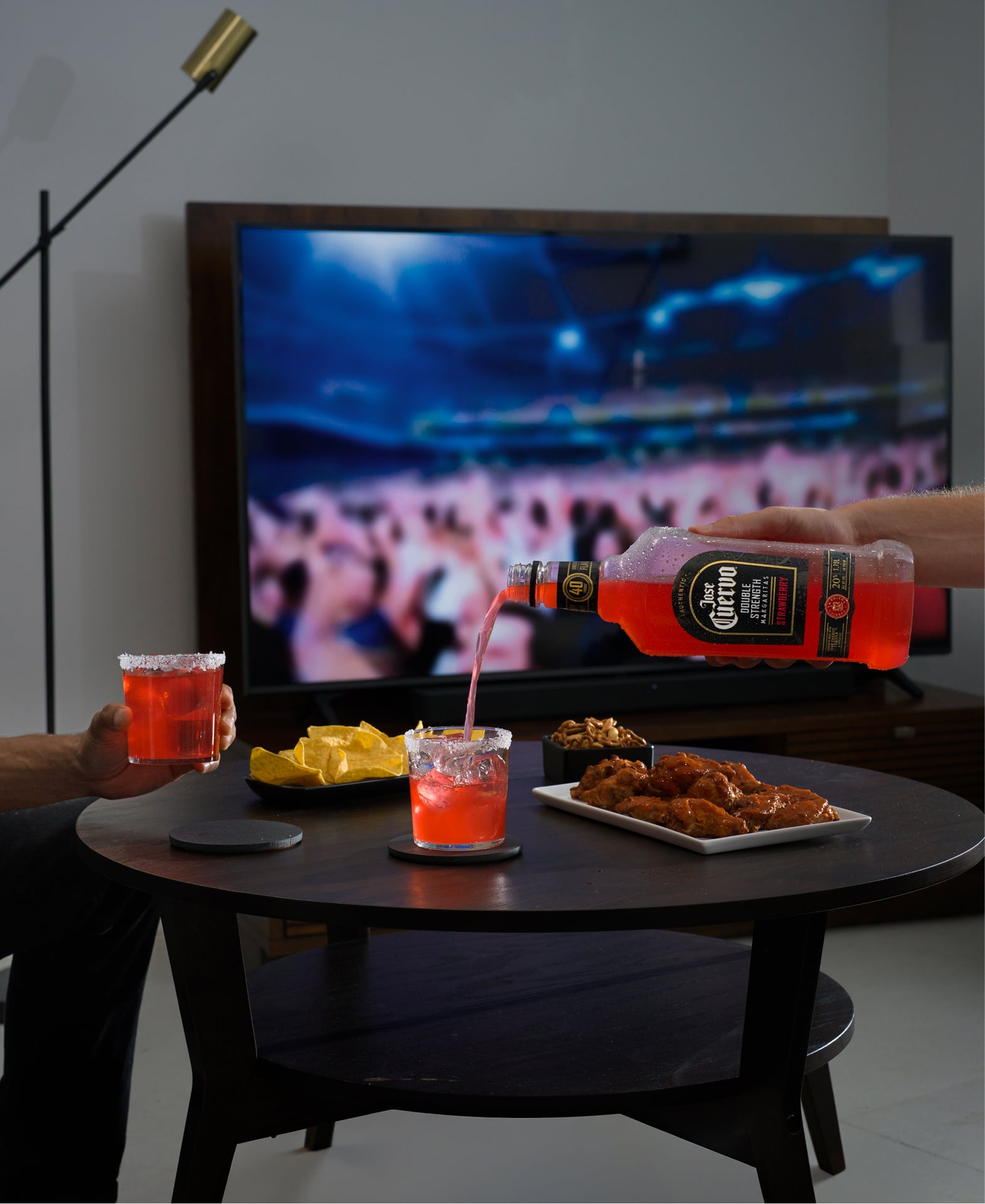 Pouring Jose Cuervo Double Strength Strawberry Margarita ready-to-drink cocktail to a glass in a living room